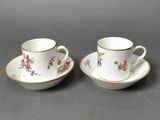 a pair of cups and saucers with floral designs on them
