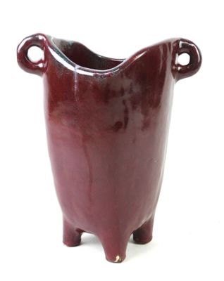 a red vase that is sitting on a white surface