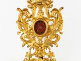une horloge dorée avec un verre rouge au milieu