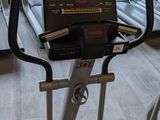 a row of tread machines in a gym with a view of trees