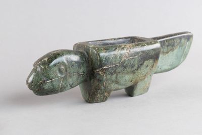 une sculpture verte représentant un éléphant sur une surface blanche