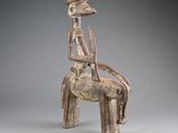 une statue en bois représentant un homme assis sur un cheval
