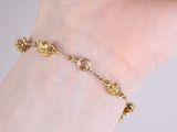 someone is holding a gold bracelet with a flower design on it