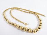 a close up of a gold beaded necklace on a white background