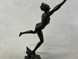 bronze statue of a boy throwing a frisbee on a rock