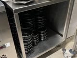 un plan de travail en inox sur lequel sont posés tout un tas de casseroles et de poêles