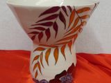 a white vase with orange and purple designs on it