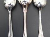 three silver spoons sitting on top of a table next to each other