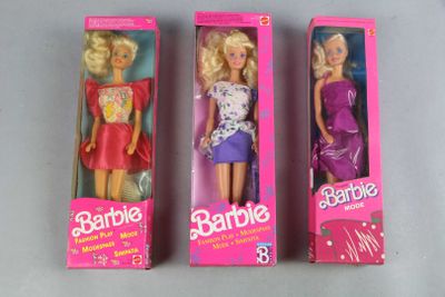 three barbie dolls are in a pink box on a table