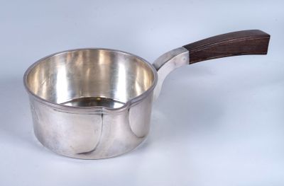 une casserole argentée avec un manche en bois posée sur une surface blanche
