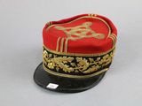 a red and black hat with a gold design on it
