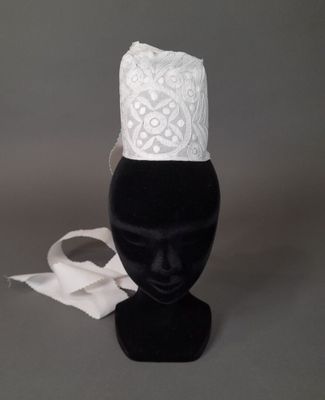 une tête de mannequin noire coiffée d'un chapeau blanc