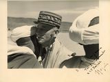 photographie en noir et blanc d'un homme coiffé d'un turban en train de parler à deux autres hommes