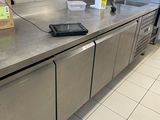 un plan de travail en acier inoxydable dans une cuisine professionnelle, avec de nombreux ustensiles accrochés au mur