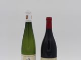 two bottles of wine sitting next to each other on a white surface