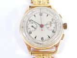 une montre-bracelet en or avec un cadran blanc sur une surface blanche