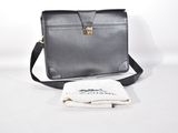 un sac noir et une serviette blanche posés sur une table