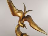 statue of a golden bird on a black base on a white background
