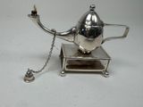 a silver teapot with a chain attached to it
