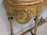 a gold console table with a mirror on top of it