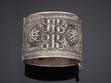 an antique silver bracelet with a cross and flowers on it