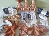 many baby dolls sitting on a bed next to other items