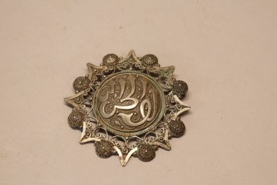 a silver medal with a star on it on a white surface