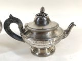two silver teapots sitting next to each other on a table