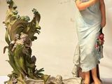 une figurine représentant une femme debout à côté d'un pot de fleurs