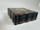 a black box with a painting on it sitting on a white surface