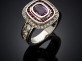 a close up of a ring with a purple stone surrounded by diamonds