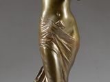 une statue antique en bronze représentant une femme, posée sur un socle en marbre
