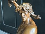 une statue en bronze représentant un homme tenant un couteau