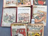 Plusieurs vieux livres pour enfants sont alignés sur une surface bleue