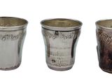 three silver cups sitting next to each other on a white surface