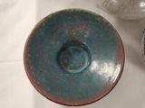 a blue and green bowl and a white vase on a table