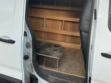 une camionnette blanche dont la porte est ouverte, garée sur le bord de la route