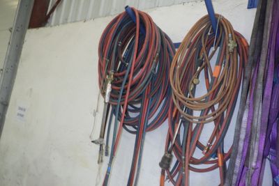 Plusieurs tuyaux sont accrochés à un mur dans un garage.