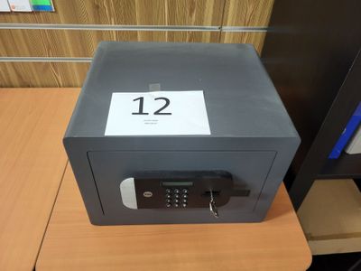 un petit coffre-fort posé sur un bureau, sur lequel figure le chiffre 12