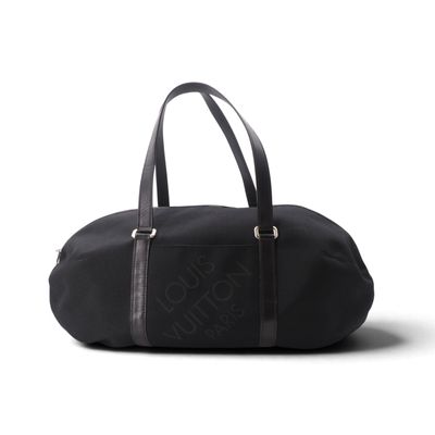 Le grand sac de voyage noir est posé sur une surface blanche.