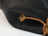 the back of a black and tan purse with a brown handle