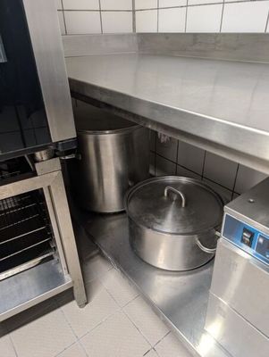 une grande casserole posée sur le plan de travail, à côté d'un four