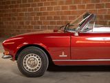 a red convertible car parked in front of a brick wall