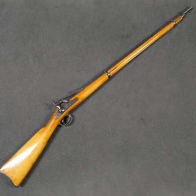 an old rifle with a wooden handle on a gray surface