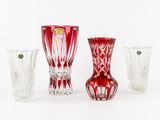 trois vases en verre rouge posés les uns à côté des autres sur une surface blanche