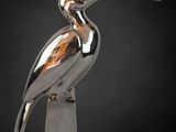a close up of a metal bird statue on a pedestal