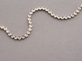 chain of silver beads with a gold clasp on a gray surface