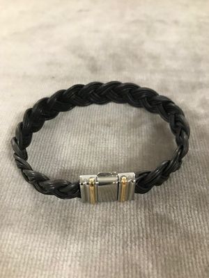 un bracelet en cuir tressé noir muni de deux fermoirs en argent
