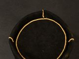 a black hat with a gold line around it on a black surface