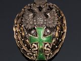 a close up of a green and gold broochle with a cross on it